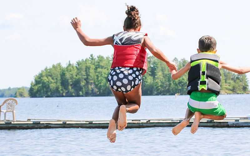 Two children jump into a lake for fun.