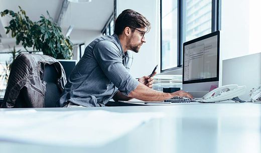 Man composes email campaign on desktop computer in office