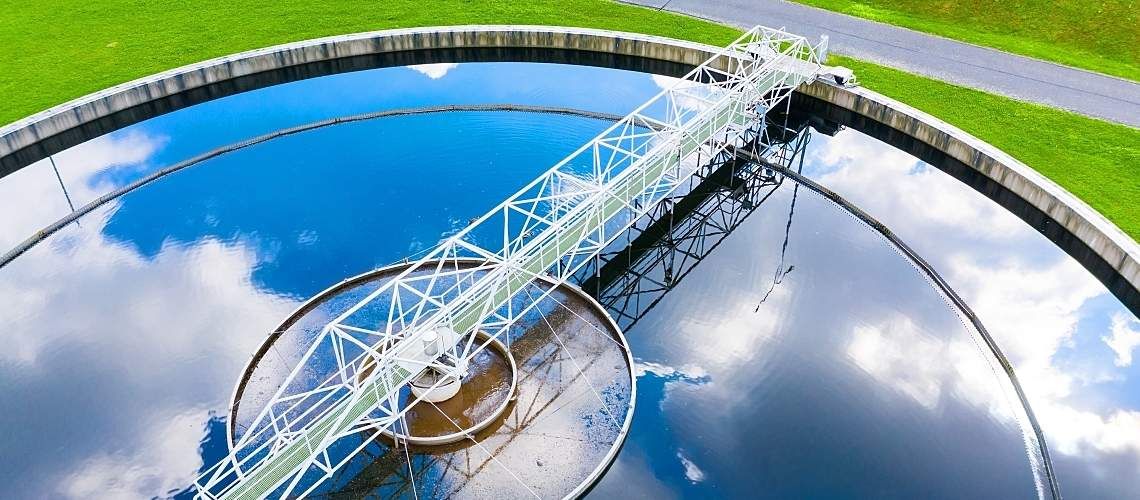 Clouds and blue sky reflected on the surface of a wastewater treatment plant clarifier.