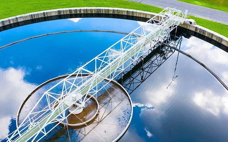 Clouds and blue sky reflected on the surface of a wastewater treatment plant clarifier.