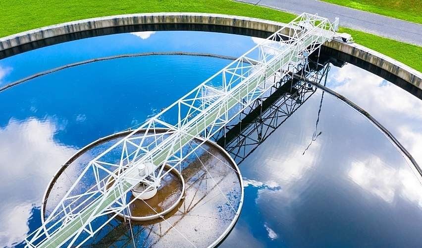 Clouds and blue sky reflected on the surface of a wastewater treatment plant clarifier.