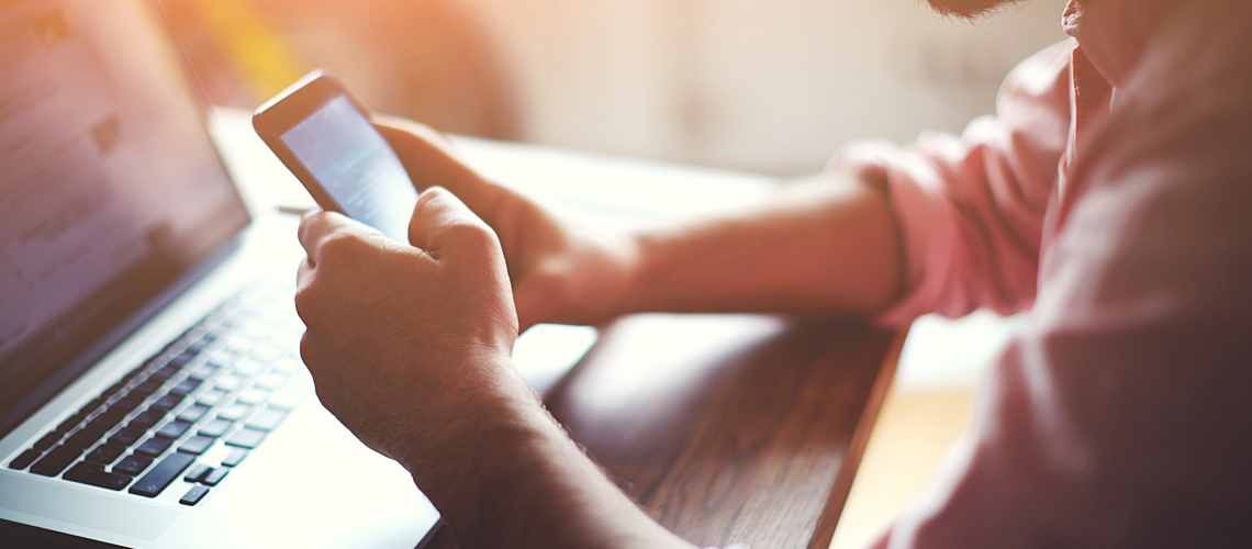 Man typing on laptop sitting at desk.